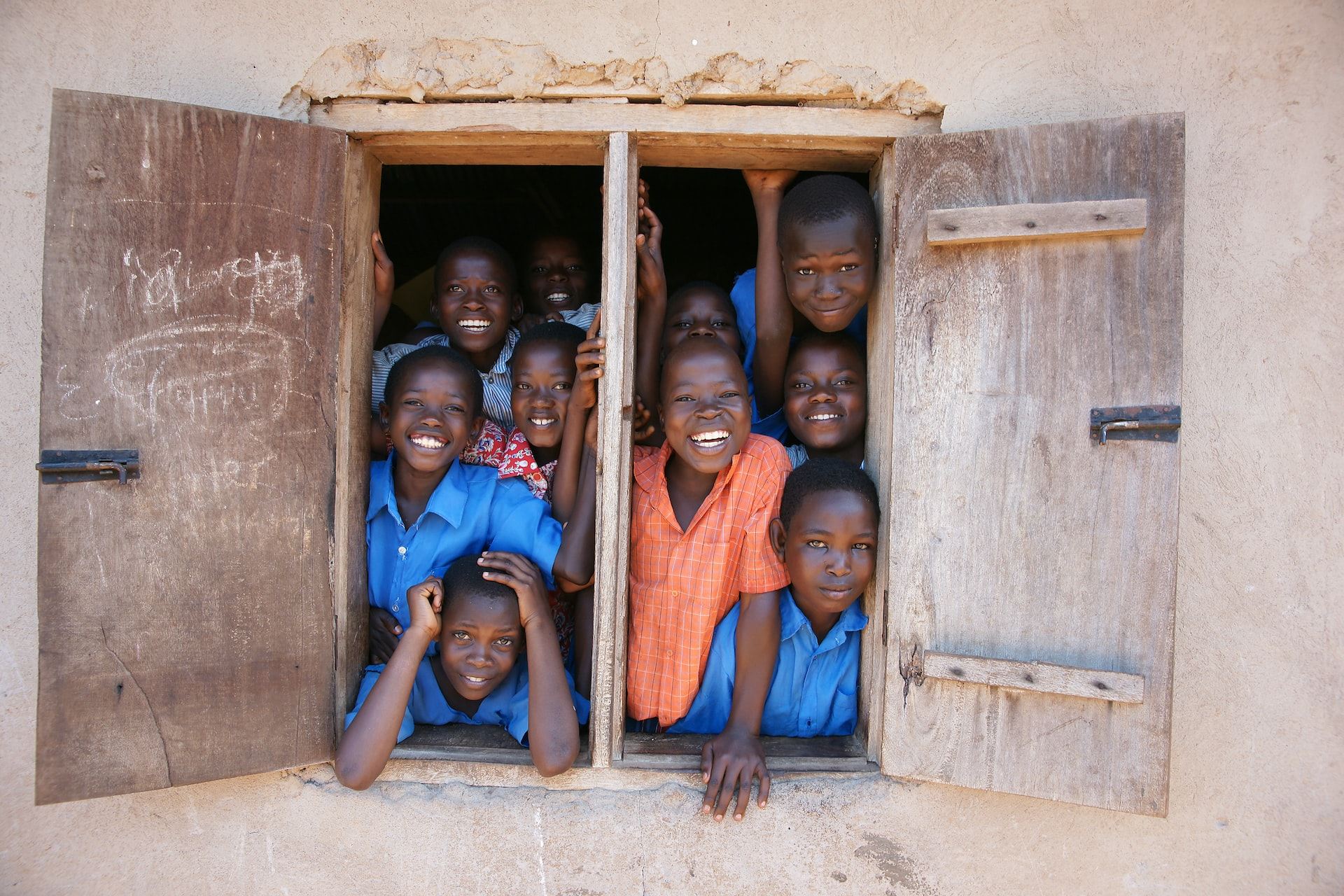 Smiling children looking out of school window in Africa